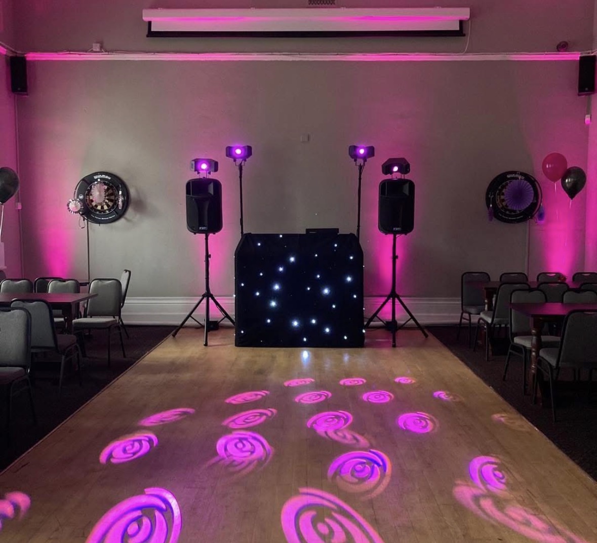 Full party setup with pink lighting and speakers in a hall