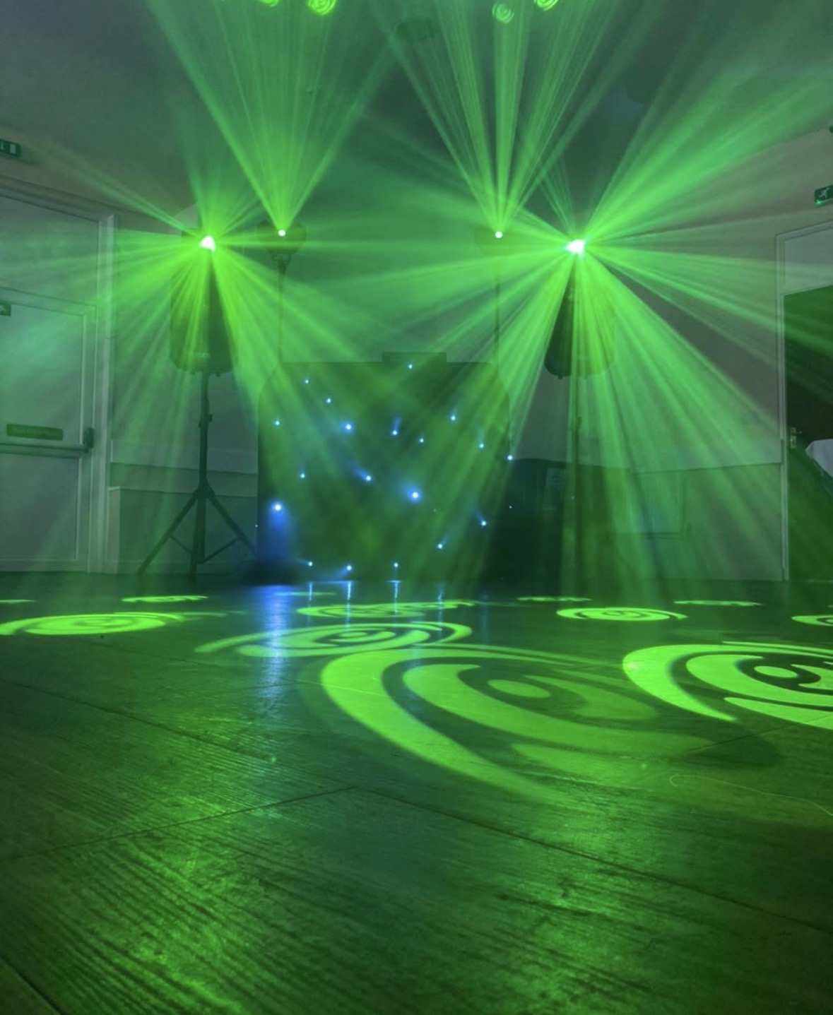 Green laser swirls projected across a dance floor